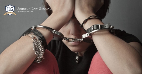 closeup of a handcuffed minor with his head on his hands